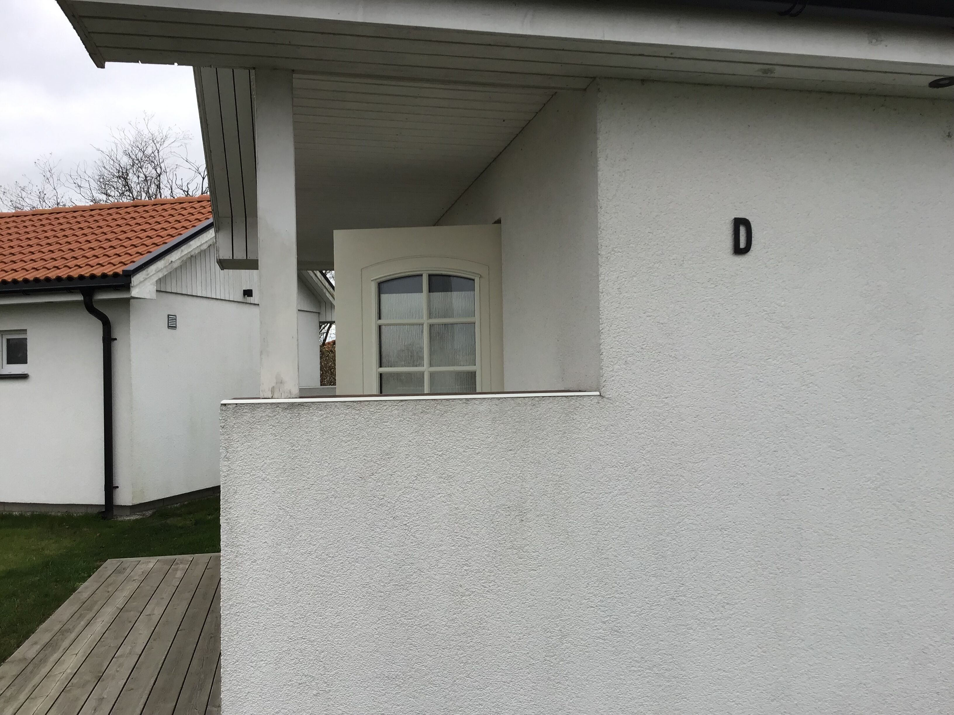 Un bâtiment blanc doté d’un porche abrité et d’une porte.
