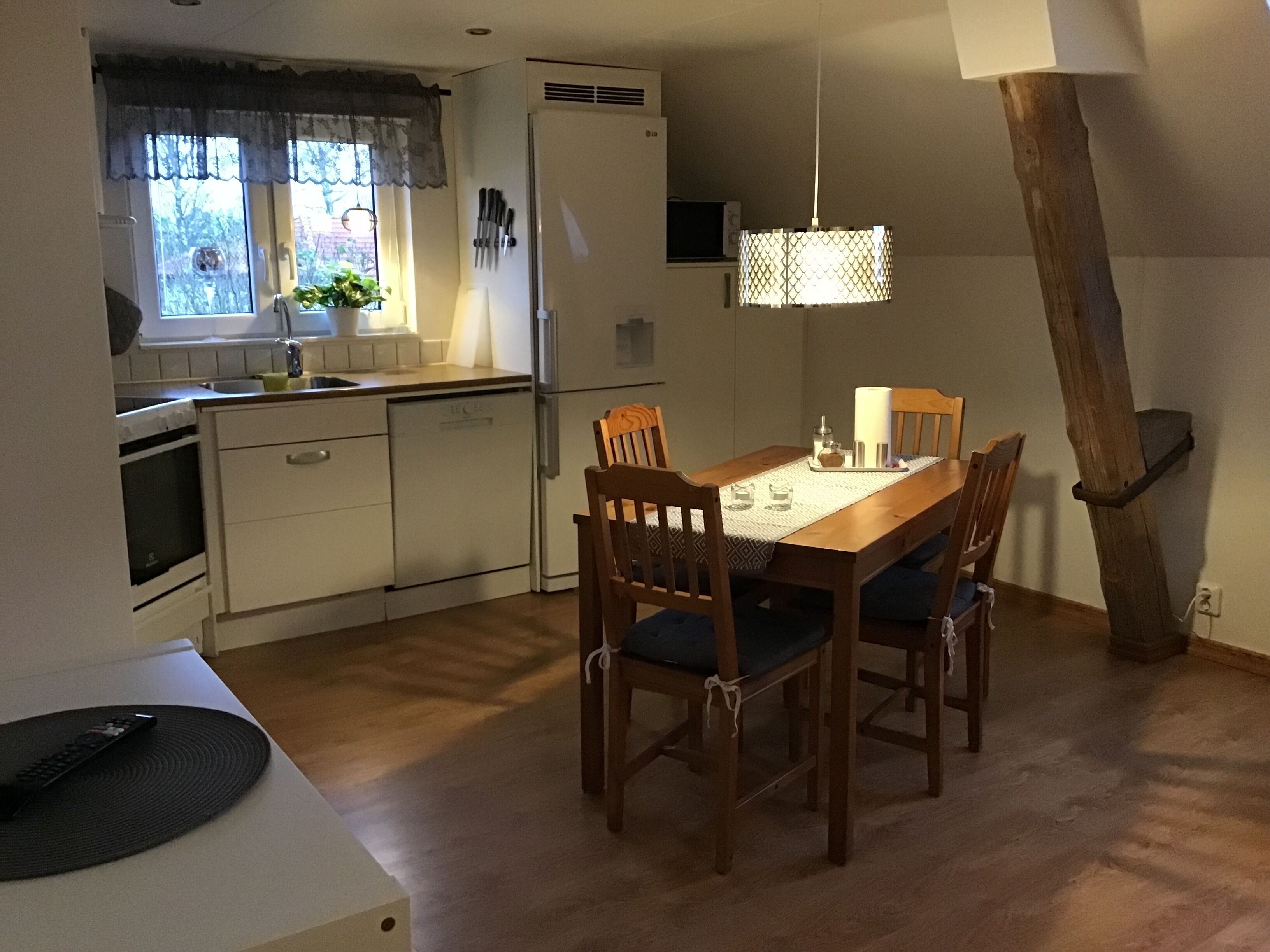 Une cuisine de taille réduite comprenant une table à manger, des chaises et un luminaire suspendu.