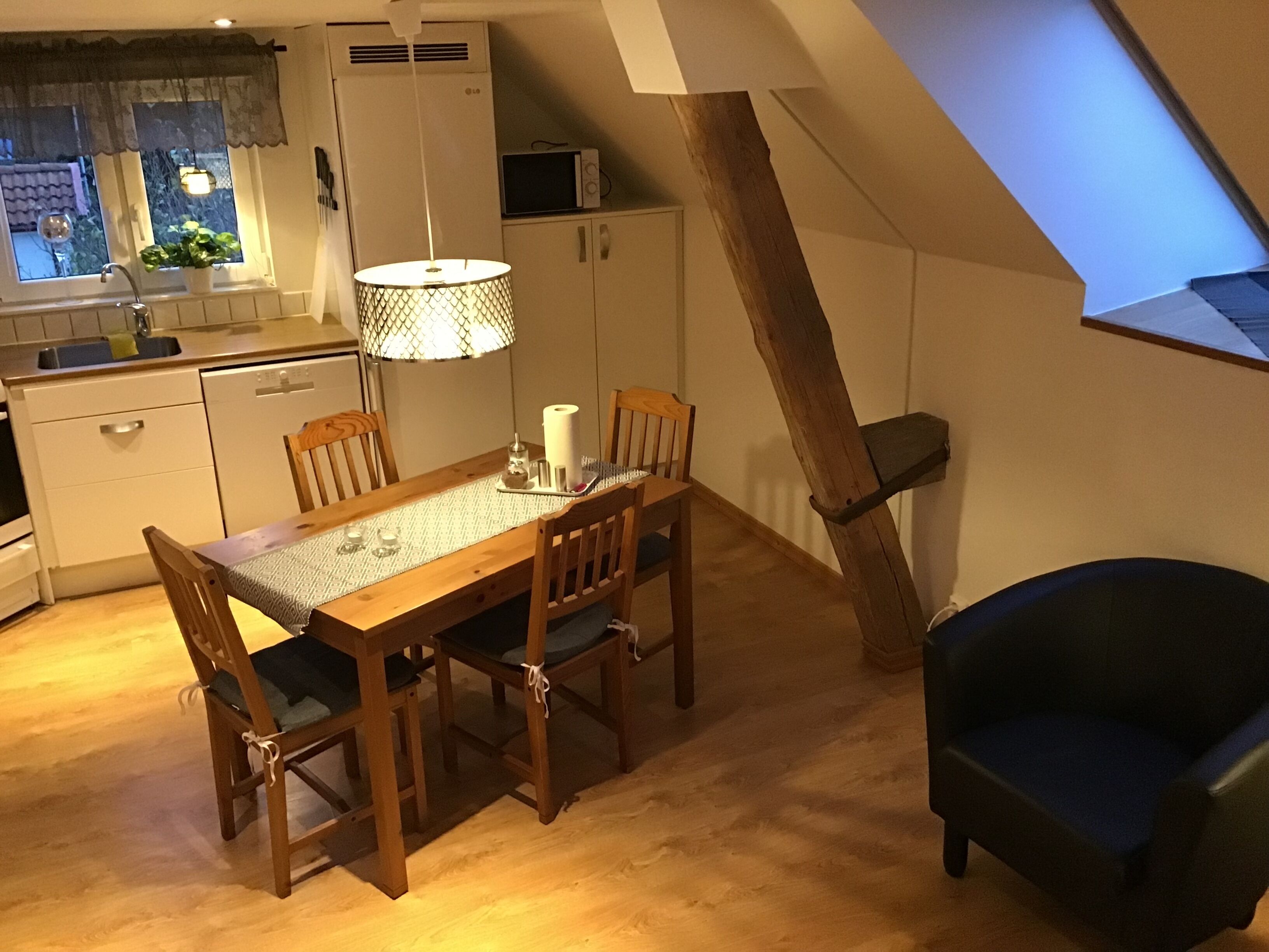Una cocina acogedora con una mesa de comedor, sillas y una lámpara colgante.
