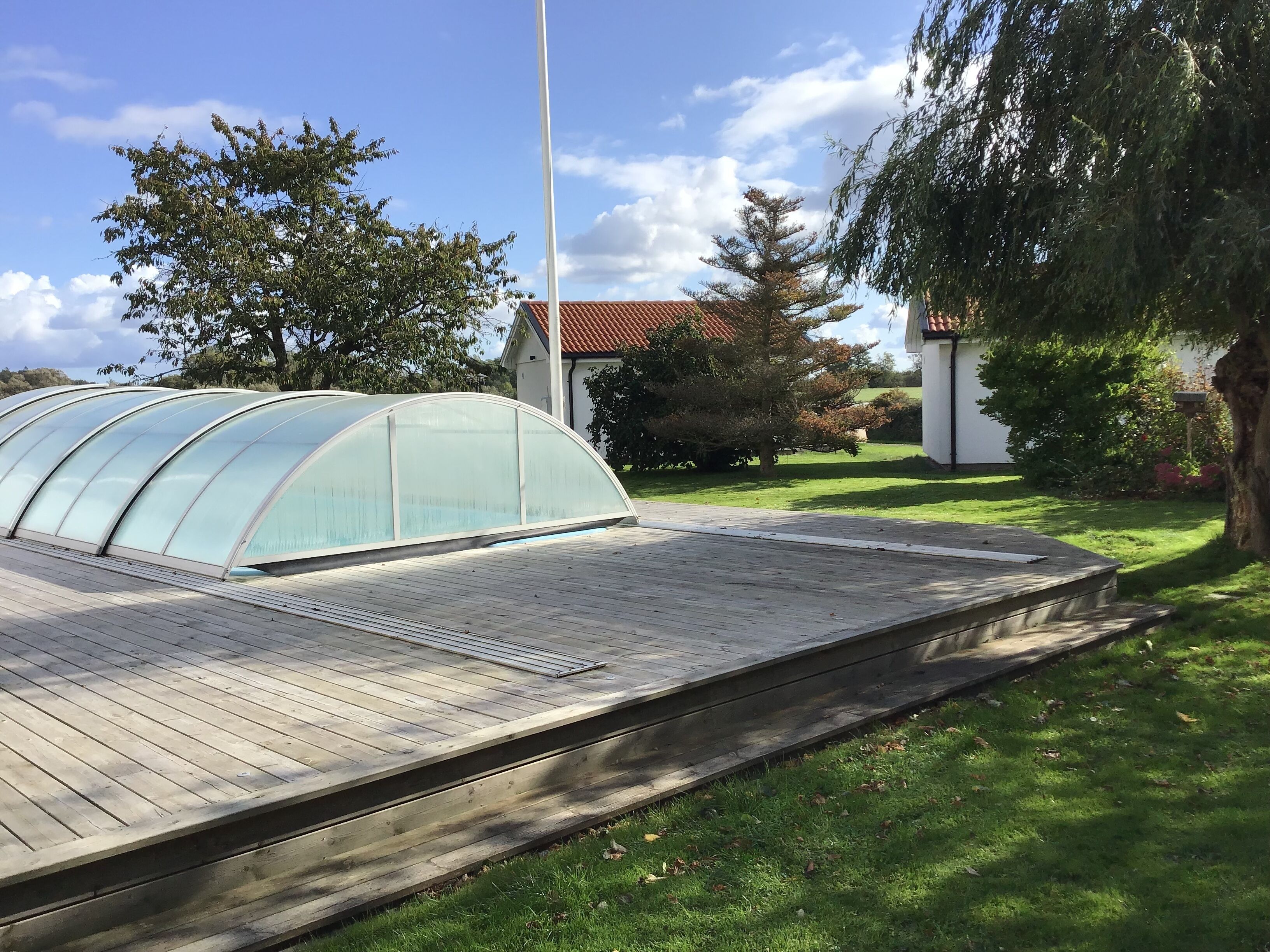 Ein Gewächshaus mit einer Holzterrasse.