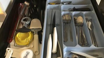 Eine Schublade mit verschiedenen Küchenutensilien, ordentlich in Fächern angeordnet.