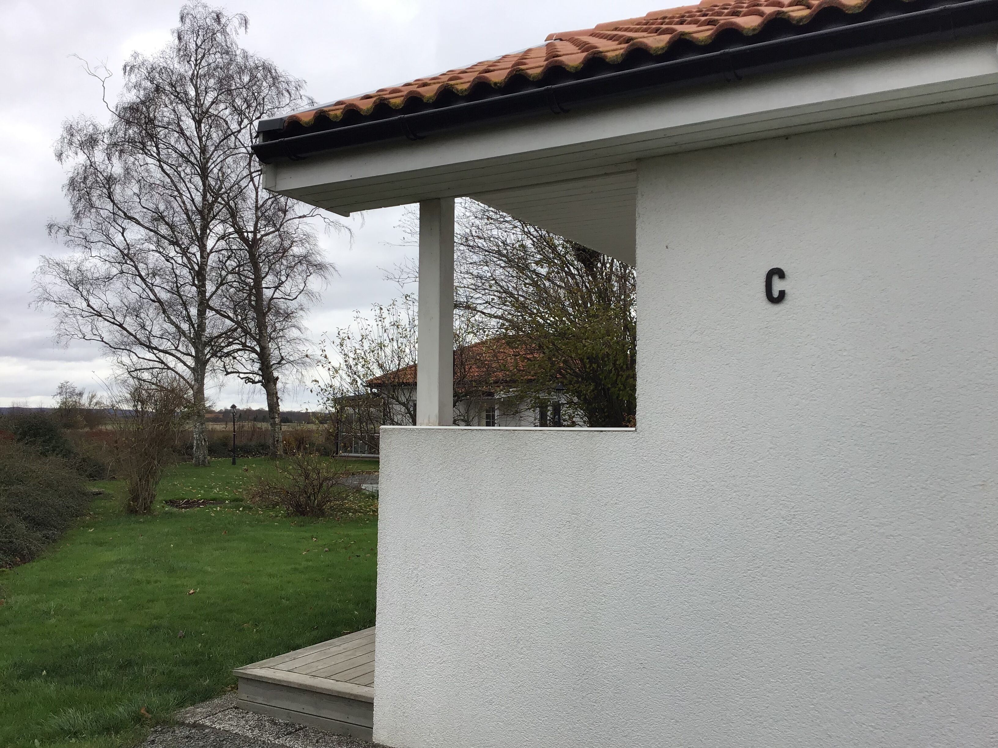 A white building with a tiled roof and a letter 'C' on the wall.