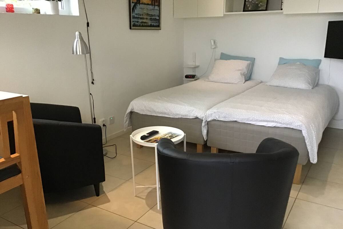 Una habitación pequeña y limpia con dos camas, un escritorio y una silla.