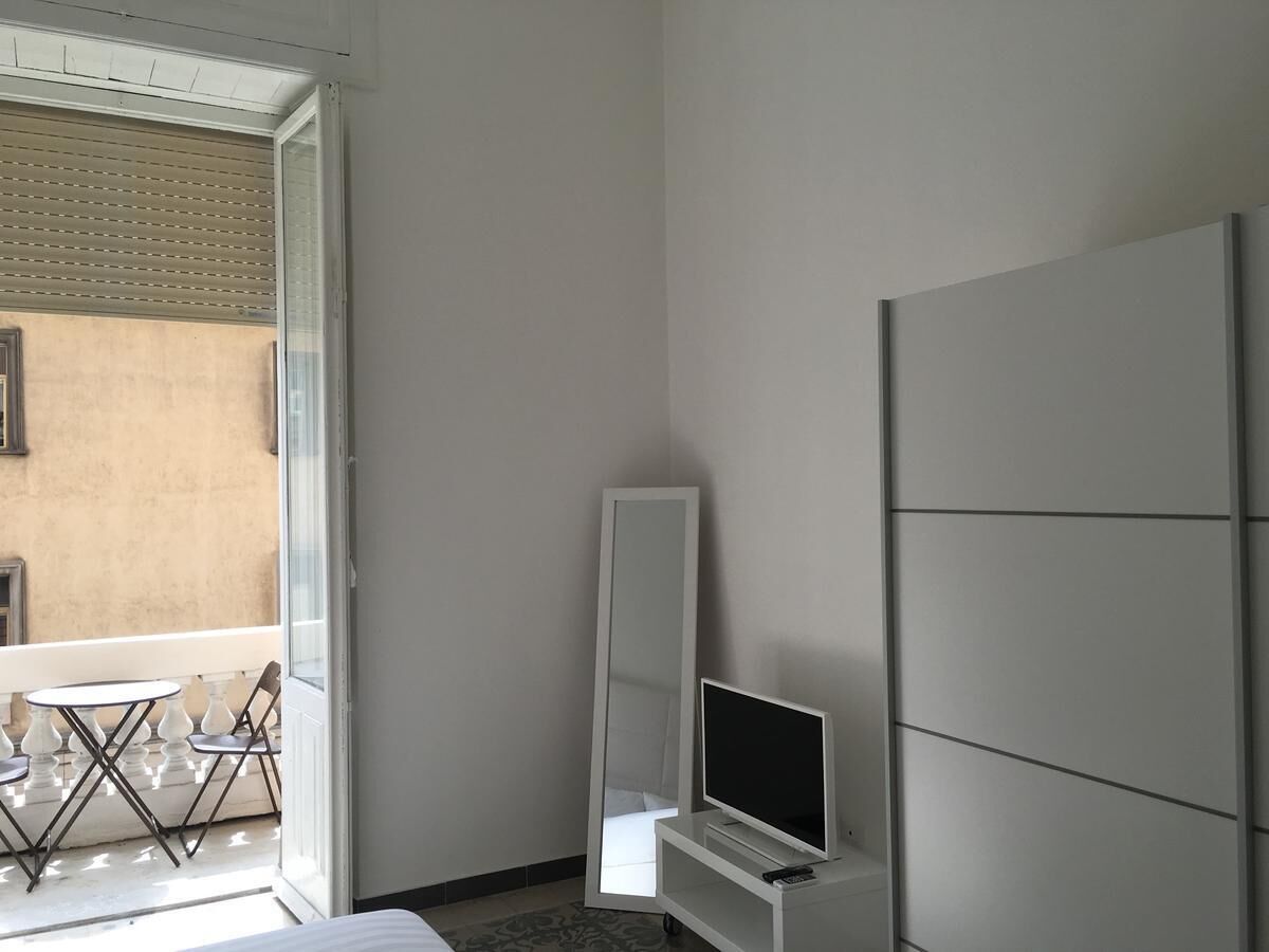 A room with a bed, a TV, a mirror, and a table with chairs.