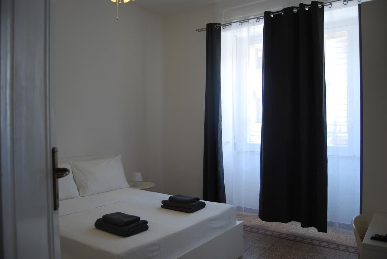 Ein Hotelzimmer mit Bett, Nachttisch, Stuhl und einem fensterbepflanzten Fenster.