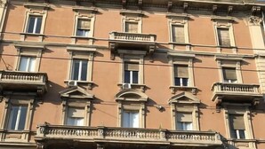 Un edificio de varios pisos con estilo arquitectónico clásico, que presenta una entrada central con un arco decorativo y un balcón superior.