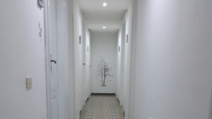 Un pasillo largo y estrecho con paredes blancas y suelo de baldosas.