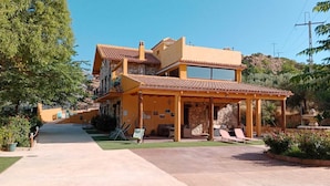 Un edificio de dos pisos con un patio, mobiliario exterior y fachada de piedra.