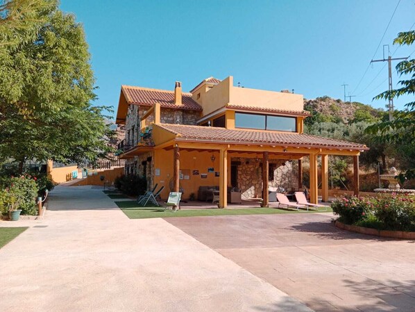 A two-story building with a patio area, outdoor seating, and a stone facade.