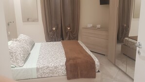 A bedroom with a bed, a dresser, a mirror, and a nightstand.
