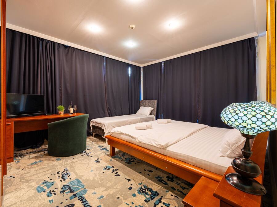 Une chambre d’hôtel avec deux lits, un bureau avec une télévision, une lampe et une moquette à motifs.