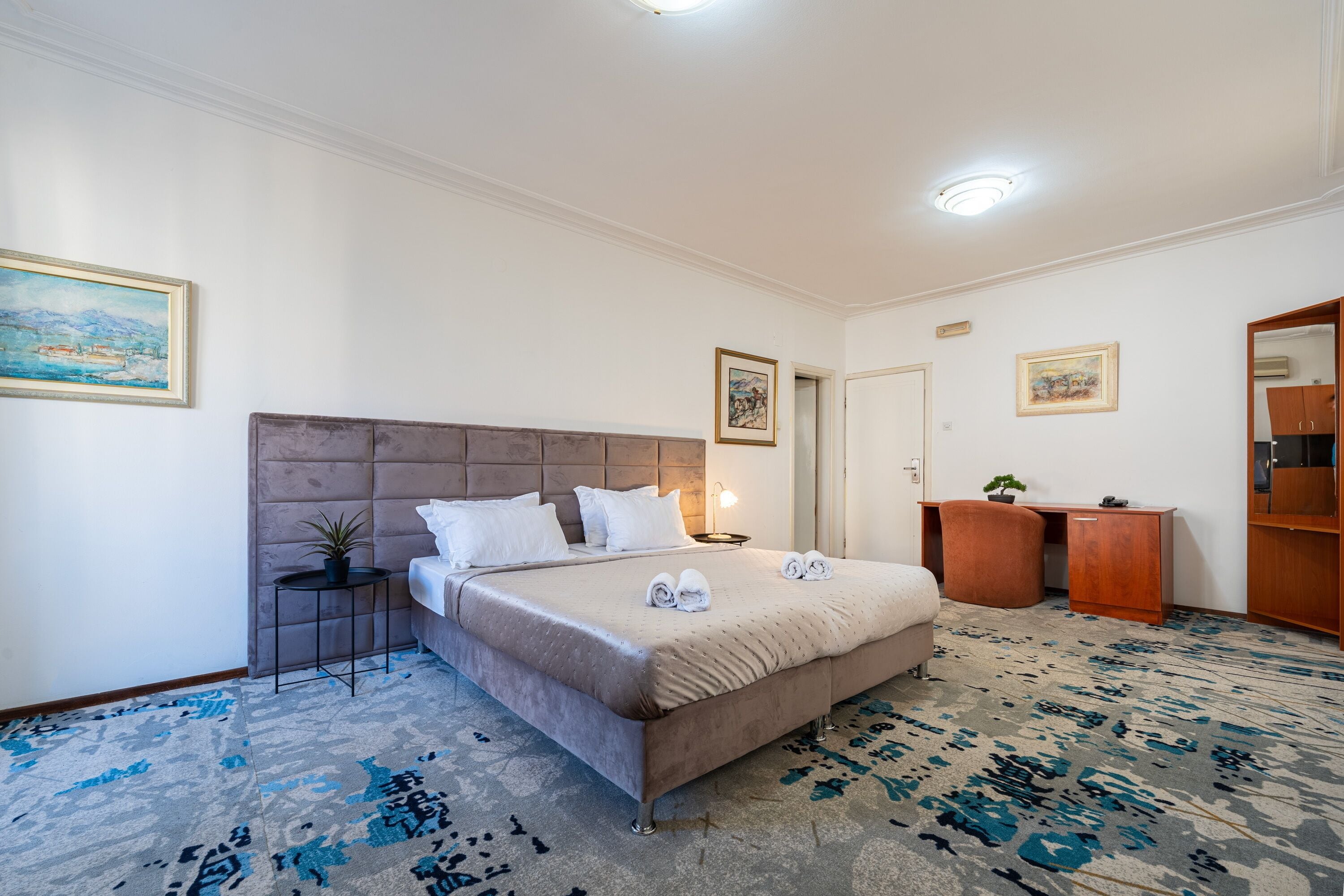 A neatly arranged bedroom with a bed, bedside table, and a desk.