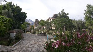 A cobblestone pathway leading through a garden with stone benches and flowering plants. - Casita Vista Alegre. (castril)