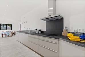 A modern kitchen with a large island, a built-in stove, and a window with a view.