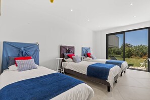 A modern bedroom with three beds, a large window, and a view of the outdoors. - VILLA LEA-5 bedrooms, swimming pool, panoramic sea view over the Gulf of Ajaccio (Grosseto-Prugna)