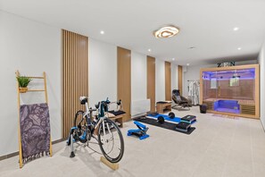 Une salle de sport moderne Ă©quipĂ©e de matĂ©riel dâexercice, dâun fauteuil de massage et dâun sauna.