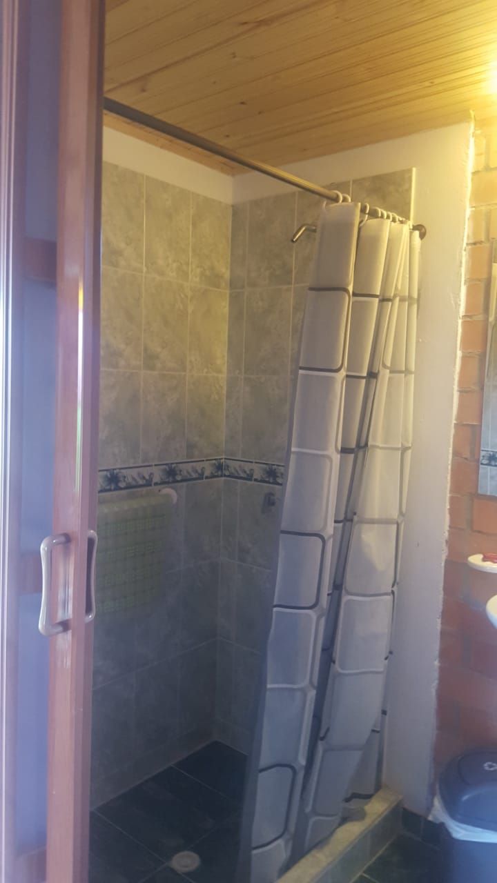 Eine Dusche mit Duschvorhang und gefliesten Wänden.