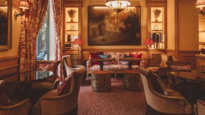 Un salon luxueux, agrémenté de meubles à motifs, d’un grand tableau et d’un lustre.