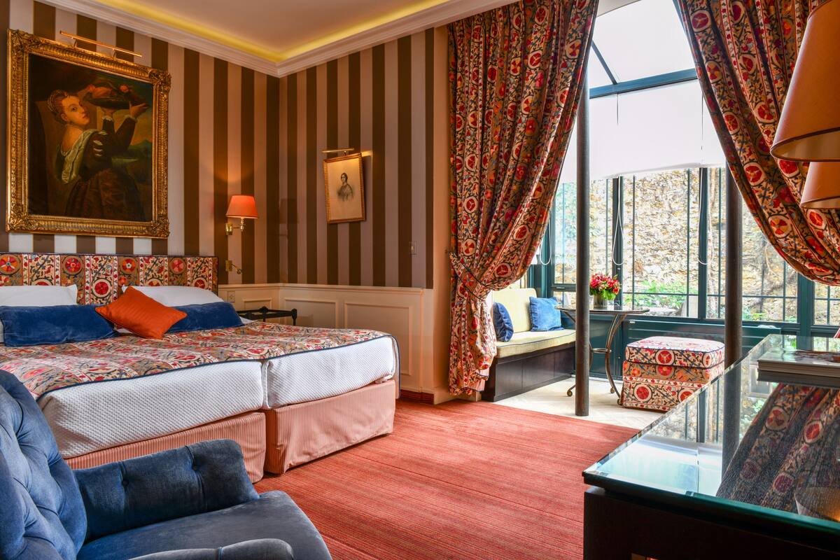 Een hotelkamer met een groot bed, een bank, een glazen tafel en uitzicht op de omgeving.