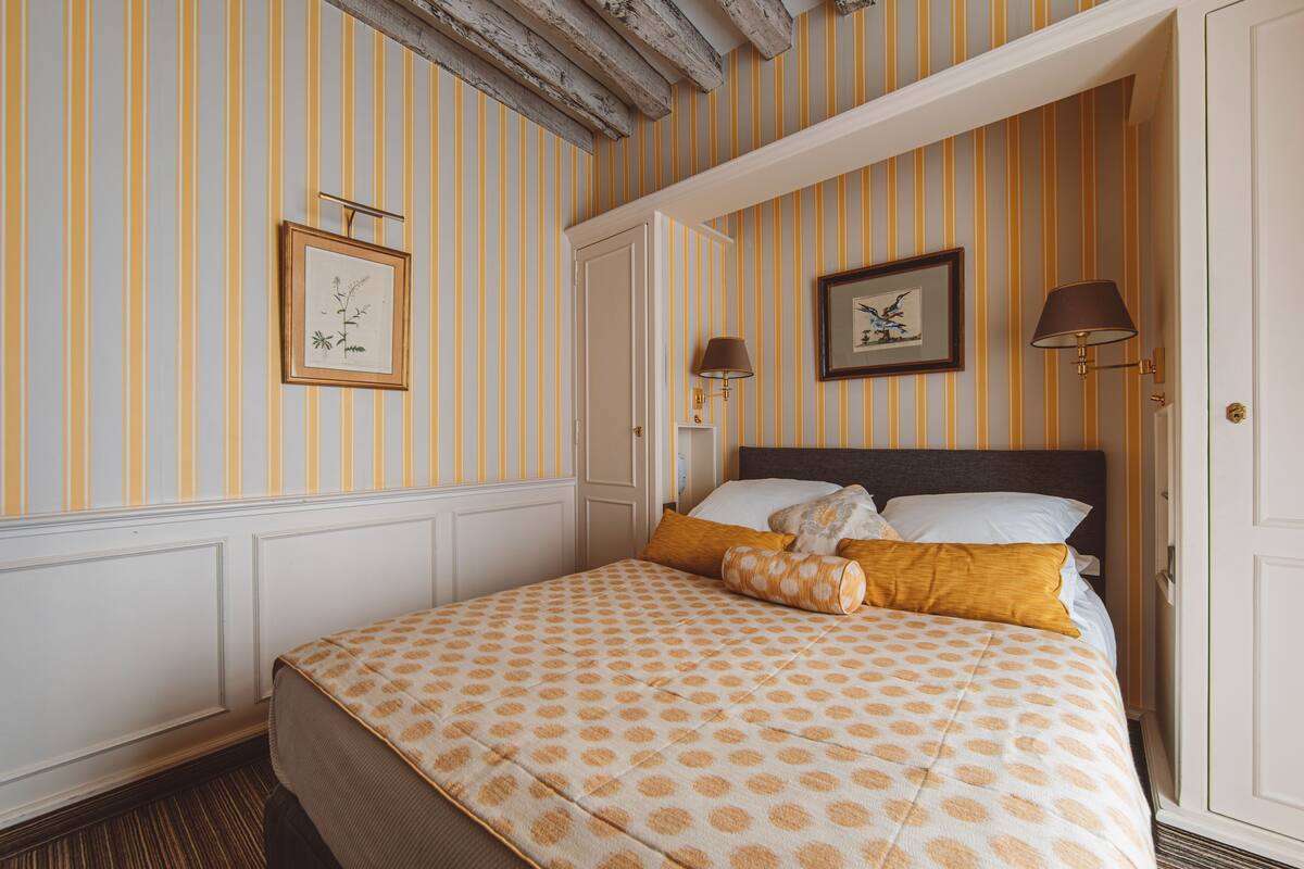 Een hotelkamer met een bed, twee ingelijste foto's aan de muur en een deur.
