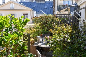 A garden patio with a table, chairs, and a bottle of champagne.