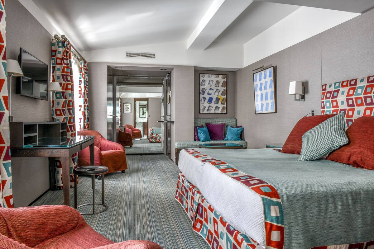 Een hotelkamer met een bed, een bureau, een stoel en een spiegel.
