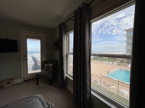A hotel room with a view of the beach and pool.