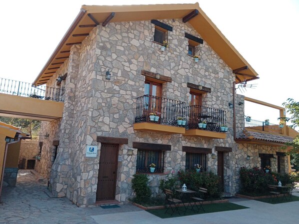 Un edificio de piedra con balcones, una puerta y un letrero que dice "Viveros Rural".