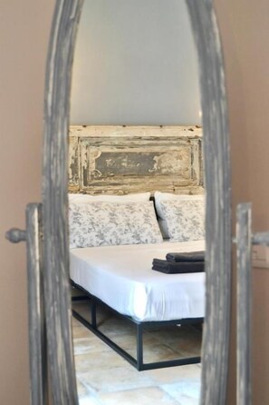 Un dormitorio con cama, almohadas y una mesita de noche.