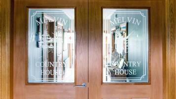 Una puerta doble de madera con paneles de vidrio esmerilado que muestra el texto "MELVIN COUNTRY HOUSE".