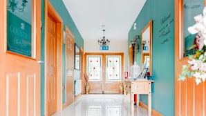 A hallway with wooden doors, a reception desk, and a chandelier.