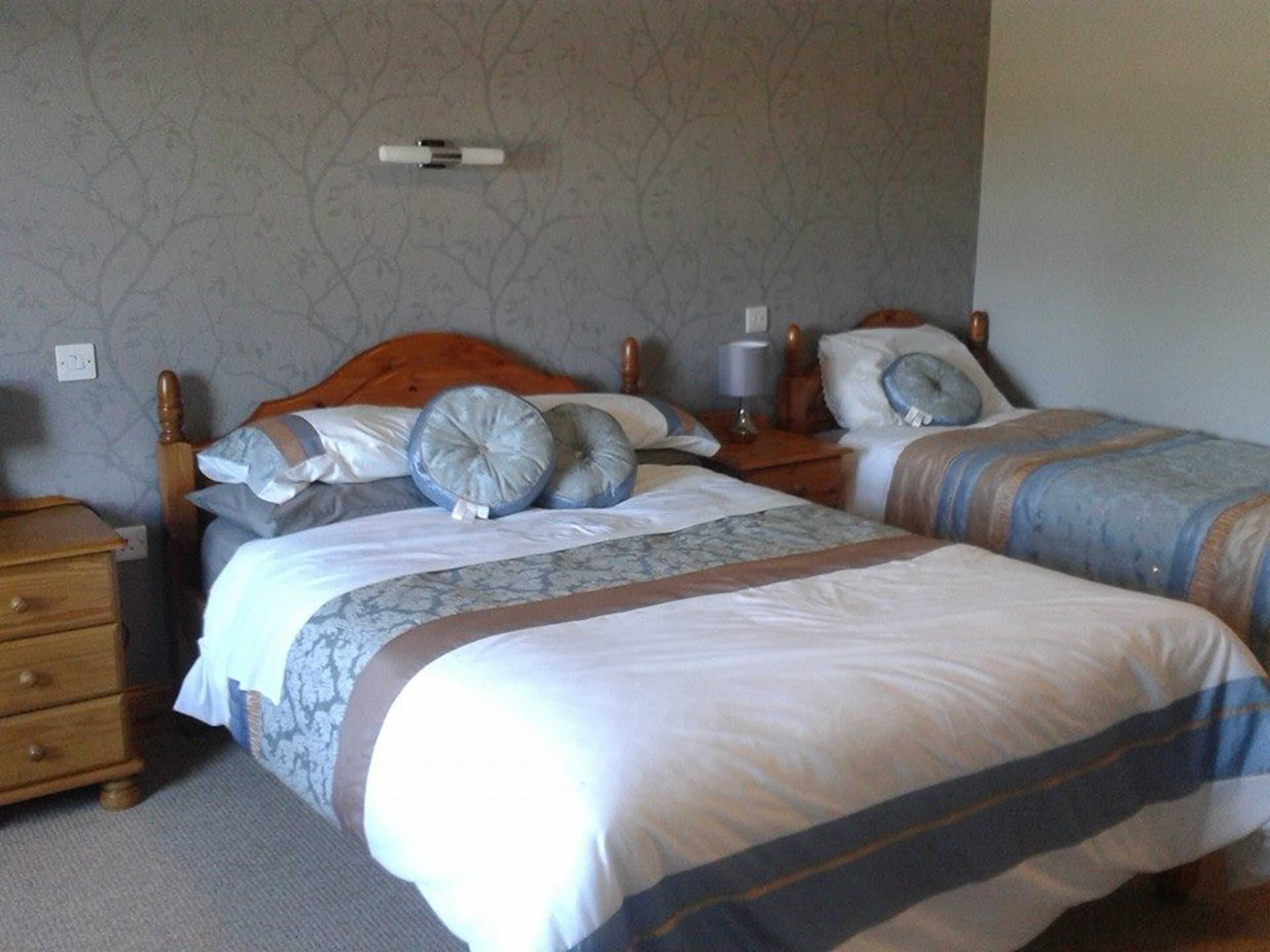 Un dormitorio con dos camas, cabeceros de madera y un papel tapiz estampado.