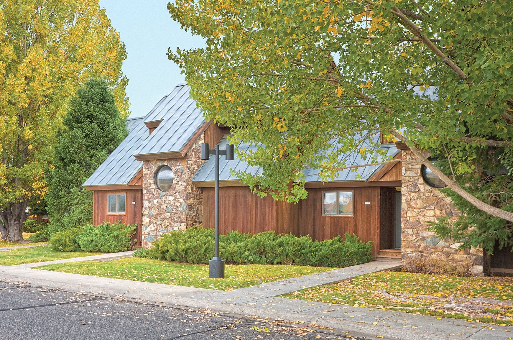 A rustic-style house with a stone facade, a metal roof, and a wooden front door.