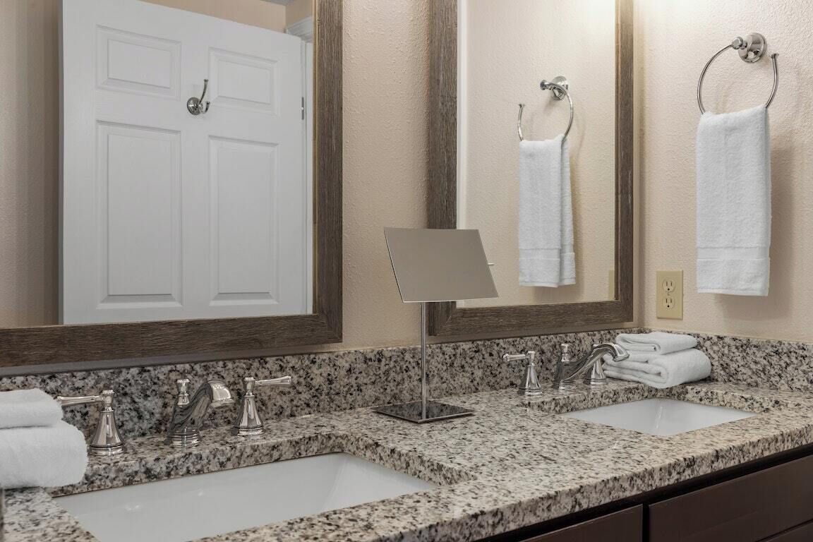 A bathroom with two sinks, a mirror, and a door.