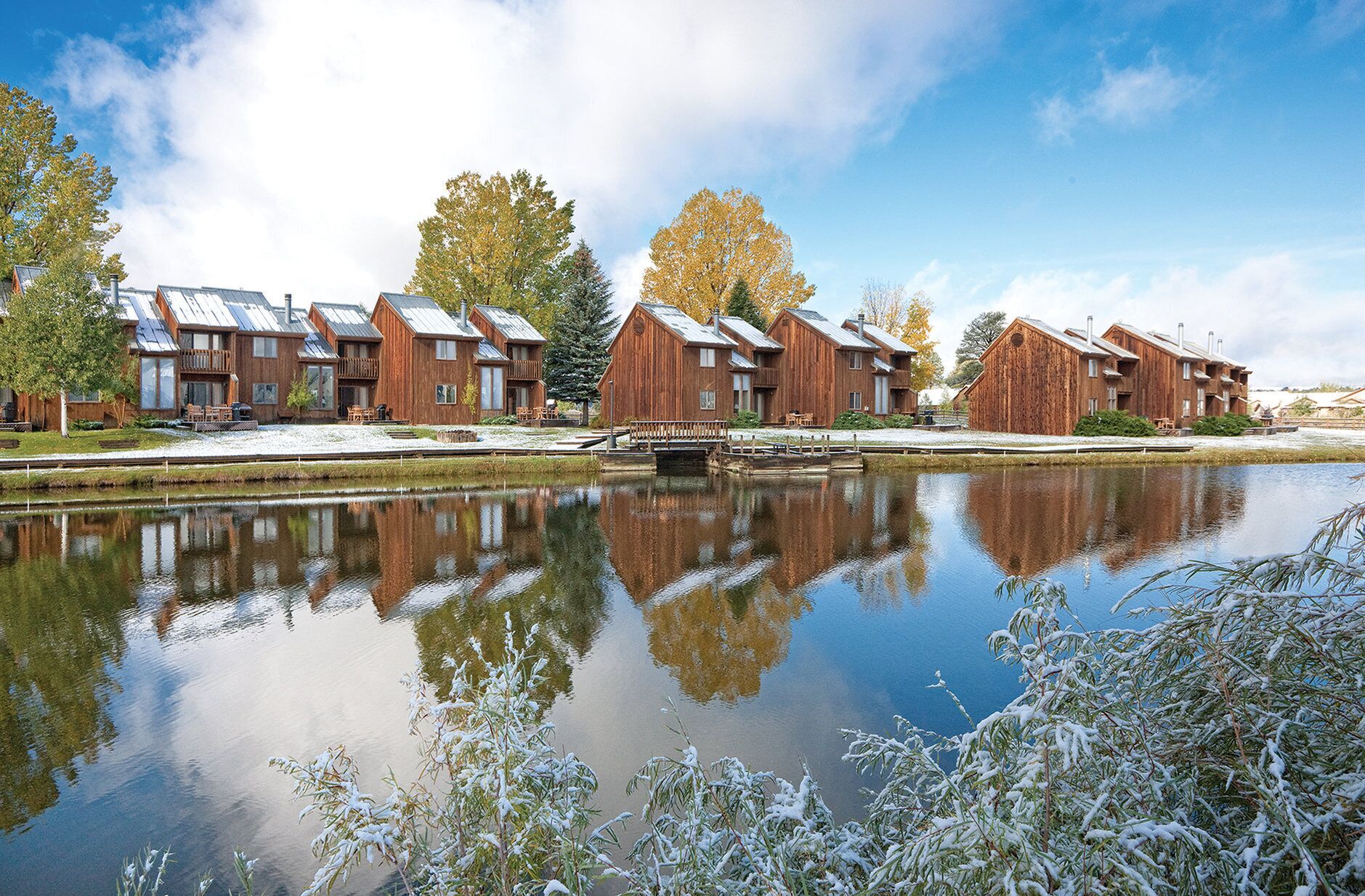 A row of wooden cabins with a canal in the foreground.