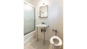 A bathroom with a white sink, a mirror, a toilet, and a shower. - OYO Hotel Holly Springs MS (Holly Springs)