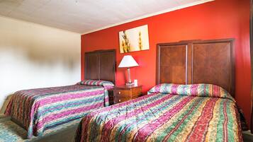 Een hotelkamer met twee bedden, een nachtkastje, een lamp en een schilderij aan de muur.