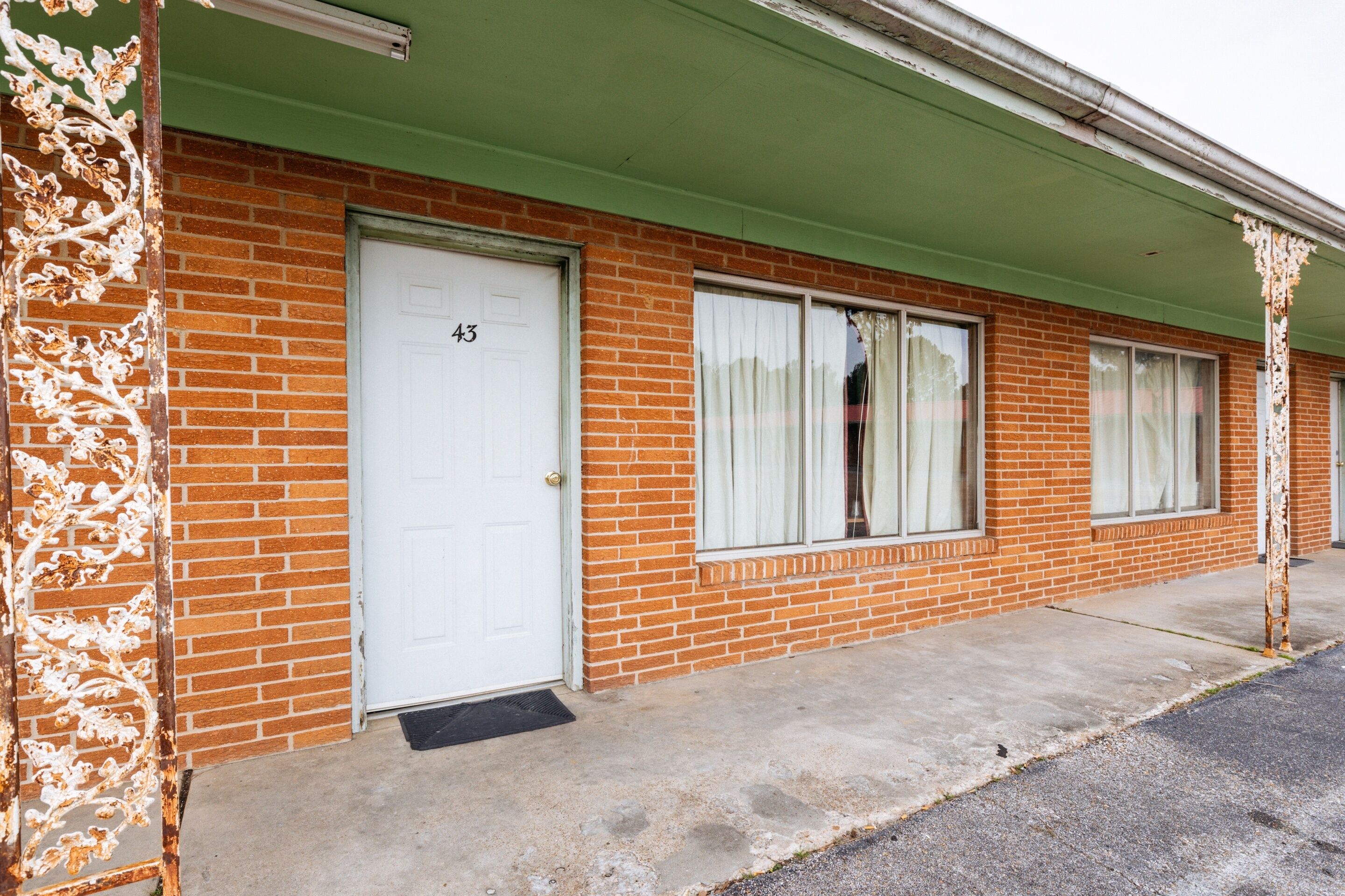 A brick building with a green roof and white doors numbered 43 and 44.