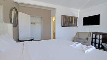 Een hotelkamer met een bed, een stoel, een televisie en een spiegel.