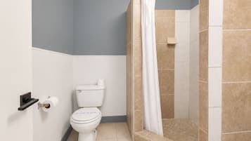Un baño con inodoro, ducha con cortina y paredes de azulejos.
