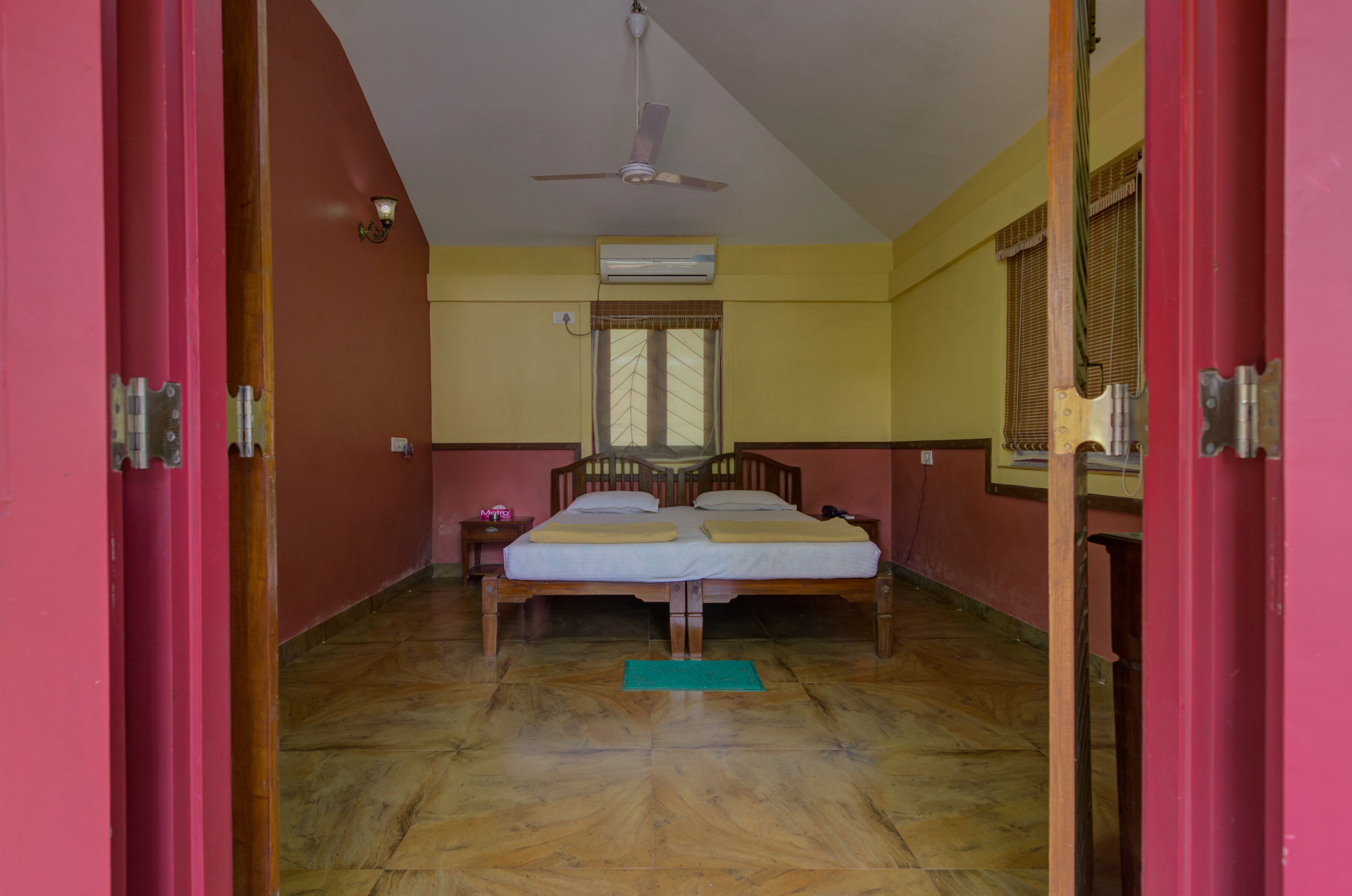 A room with two wooden beds, an air conditioning unit, a ceiling fan, and a window with curtains.