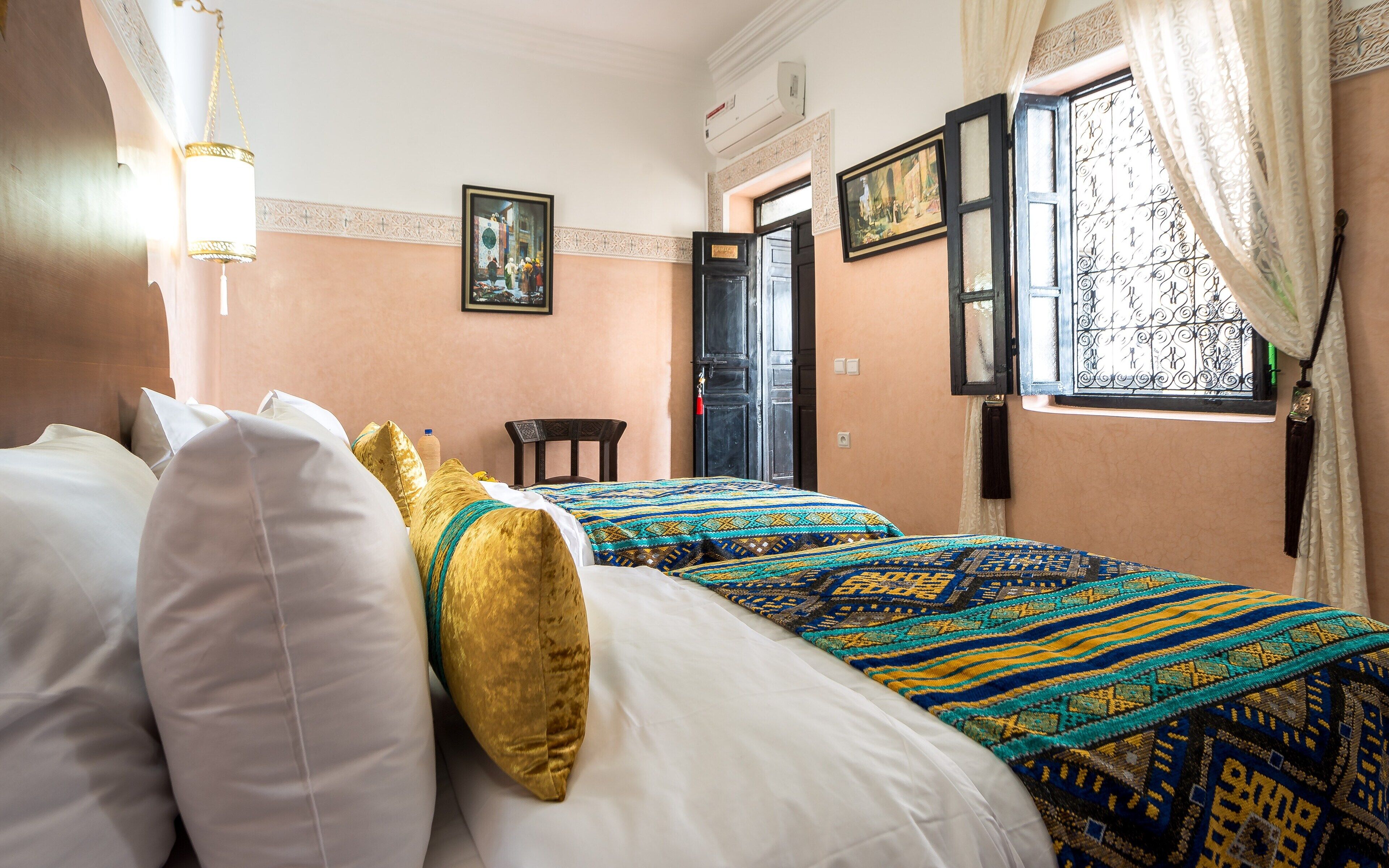 Habitación de hotel con dos camas, zona de estar y ventana con cortinas.