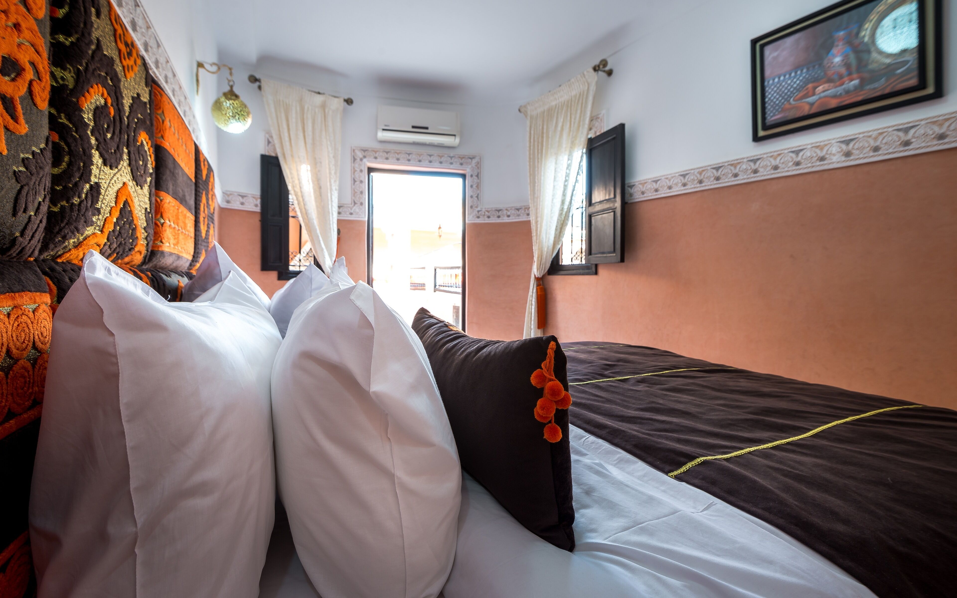 Habitación de hotel con cama, almohadas, un cuadro en la pared y un equipo de aire acondicionado.
