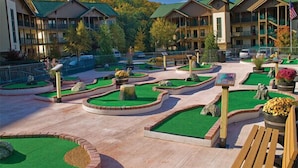 A resort with multiple-story buildings, a landscaped courtyard with green lawns and pathways, and a variety of outdoor seating areas.