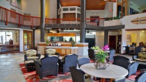 A spacious lobby with high ceilings, a central bar area, and multiple seating arrangements.