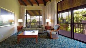 A hotel room with a large window, a sofa, a chair, a coffee table, and a lamp.