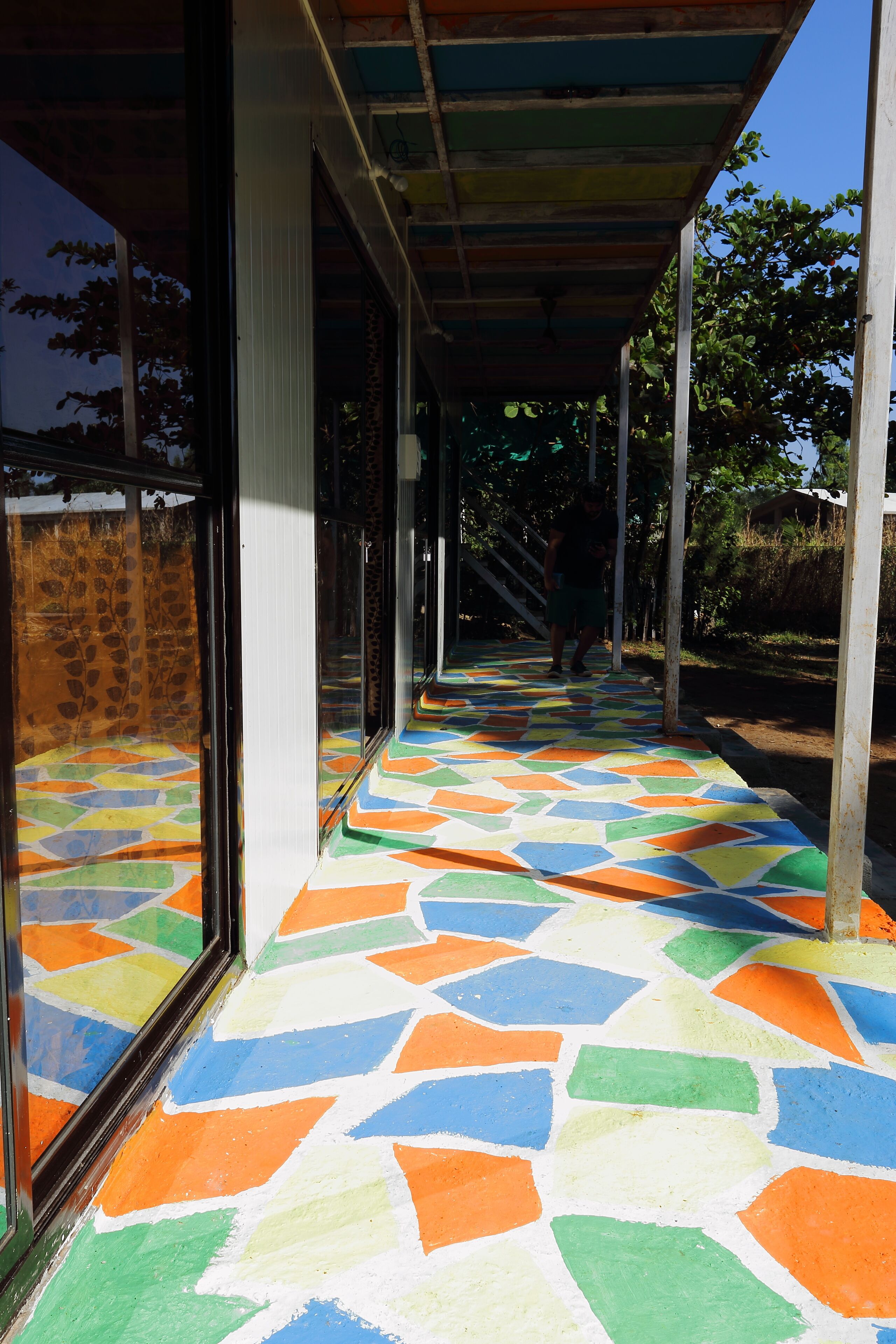 A covered outdoor area with colorful geometric patterned flooring and large windows.