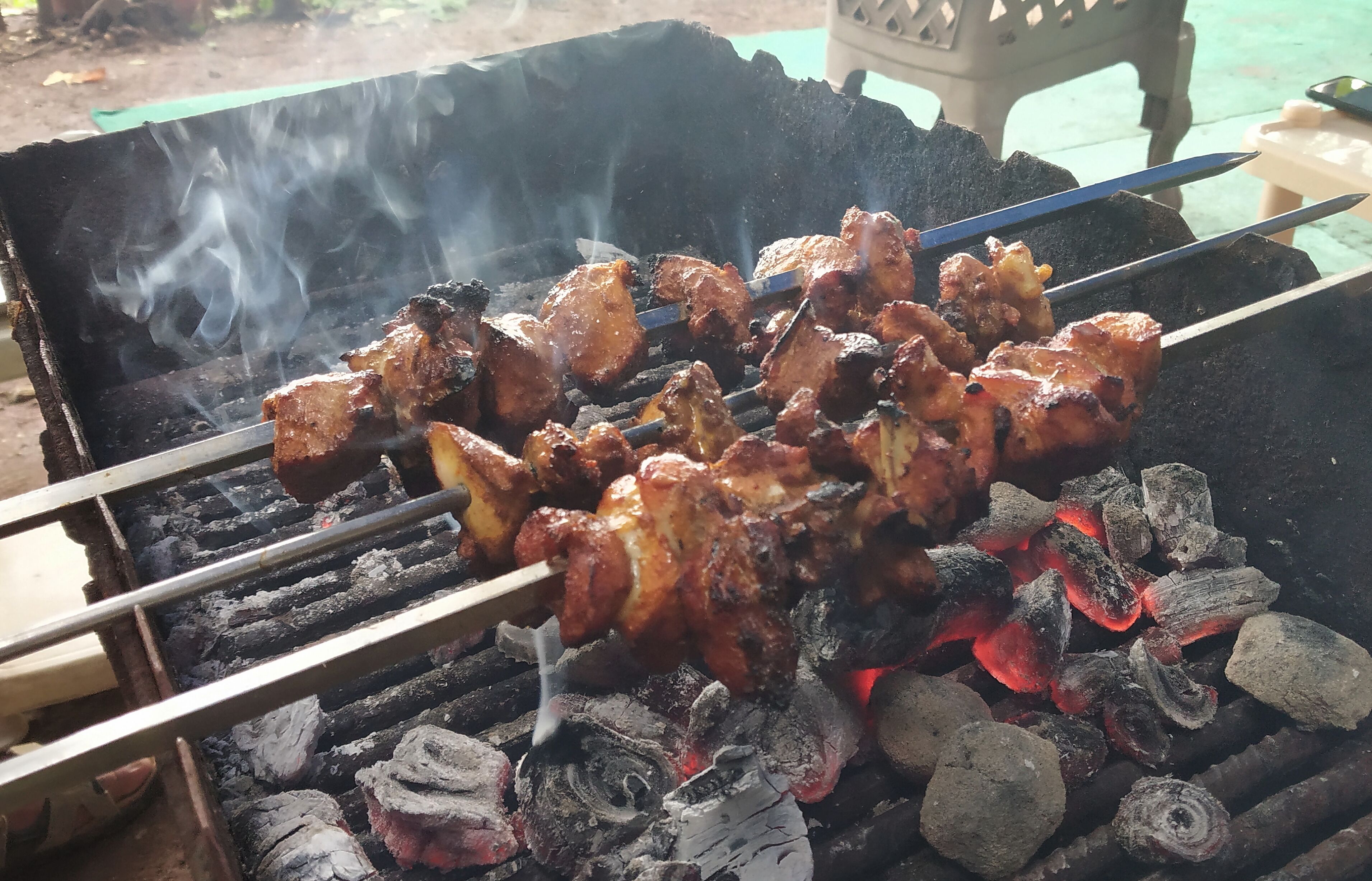 En grill med spett av kött som tillagas över kol.