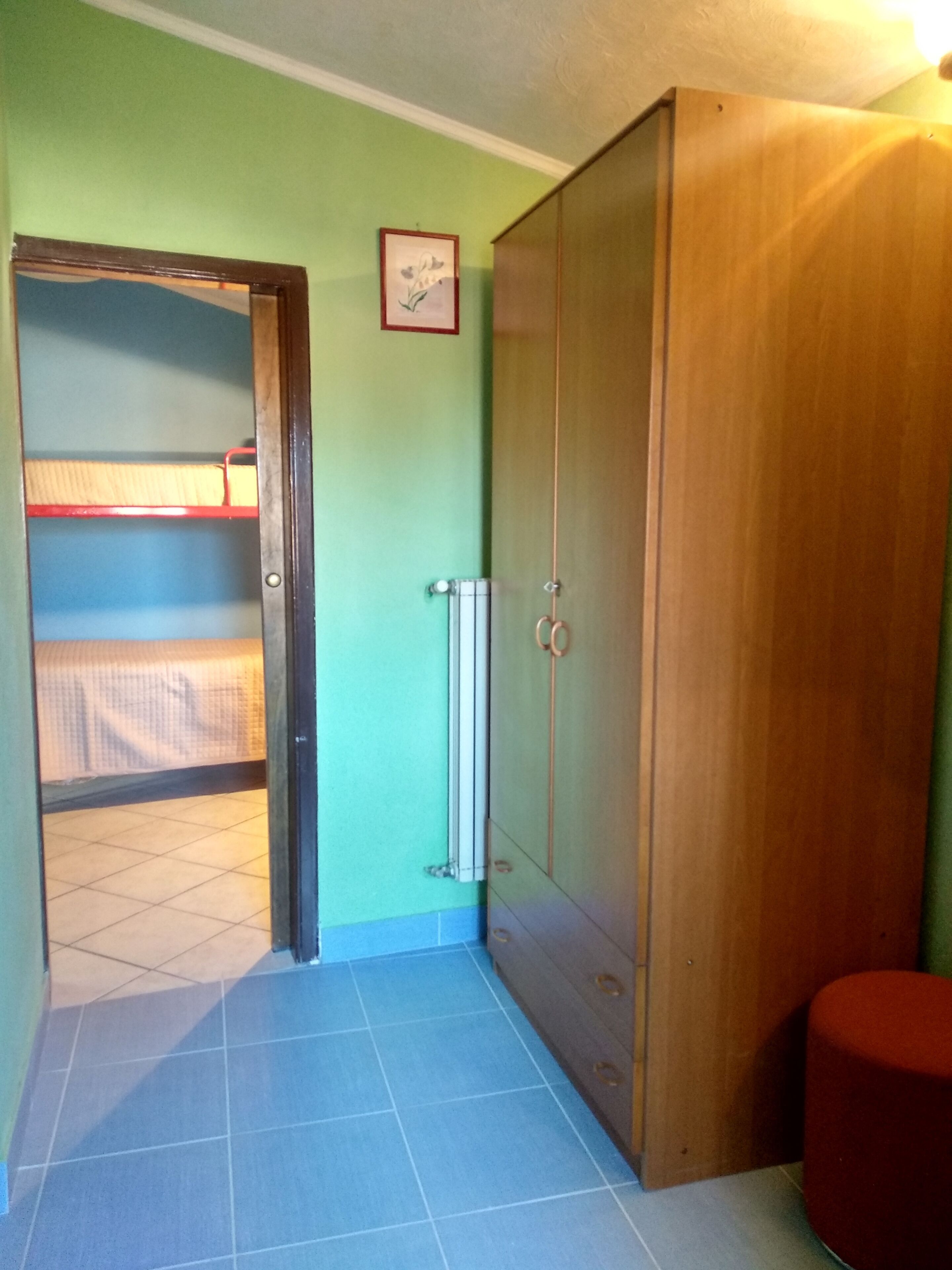 A room with a bunk bed, a wardrobe, and a radiator.