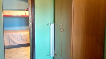 A room with a bunk bed, a wardrobe, and a radiator.